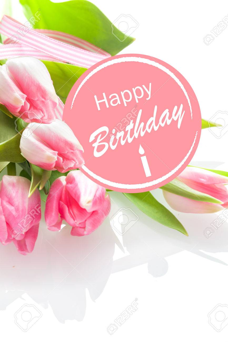 Pretty feminine Happy Birthday greeting with a festive pink rosette and a bouquet of beautiful fresh pink tulips on a white background, closeup perspective